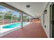 View of the covered patio leading to the screened in pool with trees visible beyond the fence at 4129 Marlow Loop, Land O Lakes, FL 34639