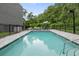 Relaxing community pool with gray lounge chairs and umbrella, enclosed by a black metal fence at 4148 Gauge Line Loop, Tampa, FL 33624