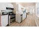 Bright kitchen features white cabinets, modern appliances, and light wood-look flooring at 4411 3Rd S Ave, St Petersburg, FL 33711