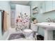Light blue bathroom with floral shower curtain, pedestal sink, and modern shelving at 5206 Cindy Kay Dr, Plant City, FL 33566