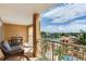 A roomy balcony has an outdoor dining table, comfortable seating, and great views of the water and nearby landscaping at 5353 Gulf Blvd # A402, St Pete Beach, FL 33706