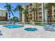 Exterior shot of a pool and hot tub surrounded by lounge chairs and palm trees at 5353 Gulf Blvd # A402, St Pete Beach, FL 33706
