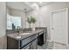 Bathroom vanity with granite counters and dual sinks, illuminated by recessed lighting, and a view into an adjacent room at 6825 Citrus Creek Ln, Tampa, FL 33625