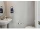 Elegant powder room with a toilet, pedestal sink, and round mirror at 6825 Citrus Creek Ln, Tampa, FL 33625