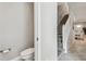 Compact powder room featuring a toilet and view of carpeted staircase at 6825 Citrus Creek Ln, Tampa, FL 33625