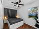 This bedroom features a queen bed with a black comforter set and a ceiling fan with an outdoor view at 7003 Yule Ln, Tampa, FL 33637