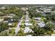 Aerial view of homes with mature trees, manicured lawns, and a tranquil pond at 709 Pinewood Dr, Dunedin, FL 34698