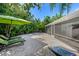 Lush backyard features travertine pavers, lounge chairs, mature landscaping, and outdoor cooking area at 709 Pinewood Dr, Dunedin, FL 34698