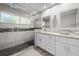 Modern bathroom with walk-in shower, double vanity with granite countertops, and stylish tile accents at 709 Pinewood Dr, Dunedin, FL 34698