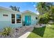 Inviting front exterior with a blue door, stone accents, and lush landscaping at 709 Pinewood Dr, Dunedin, FL 34698