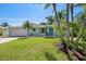 Charming, single-story home with a well-manicured lawn, palm trees, and bright blue front door at 709 Pinewood Dr, Dunedin, FL 34698