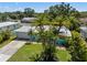 Charming, light blue single-story home with lush landscaping and a well-manicured lawn at 709 Pinewood Dr, Dunedin, FL 34698