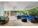 Covered patio featuring a wicker sectional, ceiling fans, and views of the tropical landscaping at 709 Pinewood Dr, Dunedin, FL 34698