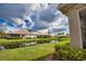 Serene backyard view with a pond, lush green lawn, and well-maintained landscaping under a partly cloudy sky at 8354 Palmetto Ct, Englewood, FL 34224