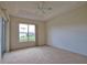 Bright bedroom featuring neutral carpet, a large window, and a tray ceiling at 8354 Palmetto Ct, Englewood, FL 34224