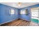 Bedroom featuring hardwood floors, blue walls, two windows with curtains, and a ceiling fan at 8396 111Th St # 301, Seminole, FL 33772
