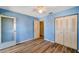 Bedroom featuring hardwood floors, blue walls, window, closet with doors, and a ceiling fan at 8396 111Th St # 301, Seminole, FL 33772