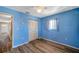 Bedroom featuring hardwood floors, blue walls, window with curtain, closet, and a ceiling fan at 8396 111Th St # 301, Seminole, FL 33772