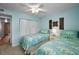 Bright bedroom features two twin beds, closet, ceiling fan and calming blue walls at 960 Virginia St # 204, Dunedin, FL 34698