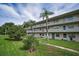 Exterior view of the condo buildings with open walkways and tropical landscaping at 960 Virginia St # 204, Dunedin, FL 34698