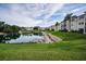 Pond view shows grassy common area, building, and blue sky with scattered clouds at 960 Virginia St # 204, Dunedin, FL 34698