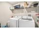 Well-lit laundry room with white washer and dryer, and overhead shelving at 10211 Cakebread Ln, Riverview, FL 33578