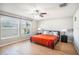 Bright main bedroom featuring a ceiling fan, hardwood floors, and two large windows at 10211 Cakebread Ln, Riverview, FL 33578