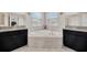 Well-lit bathroom with a corner soaking tub, dual vanities, and neutral tile at 11464 Chilly Water Ct, Riverview, FL 33569