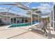 Enclosed backyard pool area with shaded seating, a barbecue, and lush greenery for privacy at 12413 Dawn Vista Dr, Riverview, FL 33578