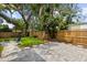 A backyard with a stone patio, green grass, a wooden fence and mature trees, creating an outdoor space at 1275 Palm St, Clearwater, FL 33755