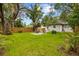 Large backyard featuring lush lawn and mature trees, with outdoor seating area for relaxation and entertainment at 1275 Palm St, Clearwater, FL 33755