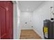 A spacious laundry room features a bright red door, vinyl flooring, and updated hot water heater at 1435 Prescott S St, St Petersburg, FL 33712