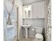 Well-lit bathroom features a pedestal sink, toilet, and shower with a patterned curtain at 15217 Octavia Ln, Odessa, FL 33556