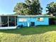 Back exterior of a blue home highlighting the screened-in patio, windows, and A/C unit at 1605 Logan St, Clearwater, FL 33755