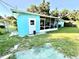 View of a blue house exterior, showing a screened-in porch and part of the backyard at 1605 Logan St, Clearwater, FL 33755