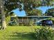 Charming single story home featuring lush landscaping, screened porch and driveway with parked car at 1605 Logan St, Clearwater, FL 33755