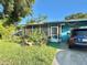 Charming single story home featuring lush landscaping, screened porch and driveway with parked car at 1605 Logan St, Clearwater, FL 33755