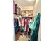 Organized walk-in closet with clothes hanging on racks and luggage stored on shelving above at 1605 Logan St, Clearwater, FL 33755