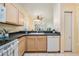 Well-lit kitchen with light wood cabinets, a white dishwasher, and an open view to the living space at 20302 Noble Oak Pl, Tampa, FL 33647
