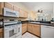 Cozy kitchen featuring white appliances, wood cabinets and a view into the living area at 20302 Noble Oak Pl, Tampa, FL 33647