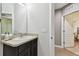 Bathroom featuring a dark vanity with light countertop, a large mirror, and an open doorway to a bedroom at 26835 Juniper Bay Dr, Wesley Chapel, FL 33544