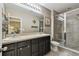Bathroom featuring dual sinks, framed mirror, a separate toilet area, and a glass shower with neutral tones at 26835 Juniper Bay Dr, Wesley Chapel, FL 33544