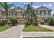Charming townhome featuring a well-maintained front yard with tropical landscaping and brick driveway at 26835 Juniper Bay Dr, Wesley Chapel, FL 33544