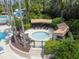 Aerial view of round hot tub with covered cabanas, surrounded by mature landscaping in a gated community at 26835 Juniper Bay Dr, Wesley Chapel, FL 33544