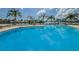 Relaxing pool with stunning water views, sun loungers, and palm trees on a beautiful summer day at 31 Island Way # 406, Clearwater Beach, FL 33767