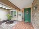 Charming front entrance with a decorative green door, a 'Welcome' mat, and a well-maintained garden at 3325 Schefflera Rd, Tampa, FL 33618