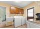 Functional laundry room with oak cabinets, washer, dryer, utility sink, and access to the backyard at 3325 Schefflera Rd, Tampa, FL 33618