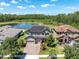 Aerial view of a beautiful house with a brick driveway, lush landscaping, and a serene lake backdrop at 3477 Barbour Trl, Odessa, FL 33556