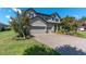 Attractive exterior with a paved driveway and a three-car garage, complemented by lush trees and landscaping at 3477 Barbour Trl, Odessa, FL 33556
