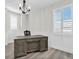Home office with large wooden desk, white wainscoting, modern chandelier, and plantation shutters at 3477 Barbour Trl, Odessa, FL 33556